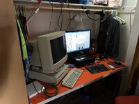 picture of my desk, an orange dinner table inside a wide-shallow bedroom closet. on the left is a mac 6200 with a mac color display 16 and a smaller apple keyboard II, on the right is a fujitsu excelbox with a 24-inch 1920x1080 display, hooked to a usb thinkpad keyboard
