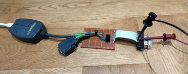 A Farallon EtherMac AAUI/10BASE-T MAU has had its AAUI cable cut and spliced onto a prototyping circuit board, where a 12V to 5V buck converter also sits. On the other end of the board is a short ribbon cable leading to a 15-pin D-sub connector, which has some power leads connected to it. A few LEDs on the Farallon adapter are illuminated.